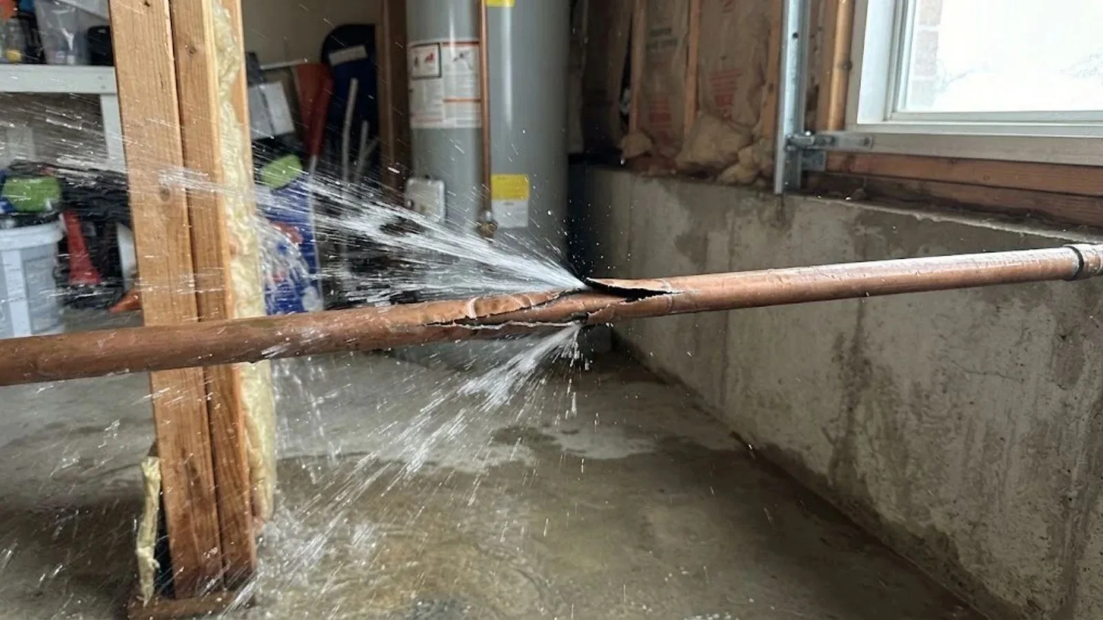 Burst pipe spraying water in a basement