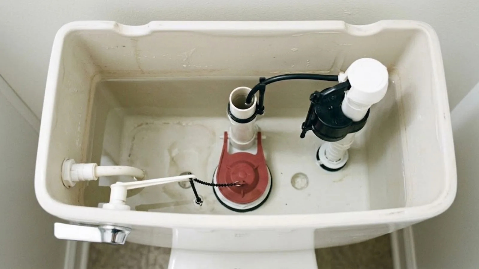 Open toilet tank showing the flapper and fill valve